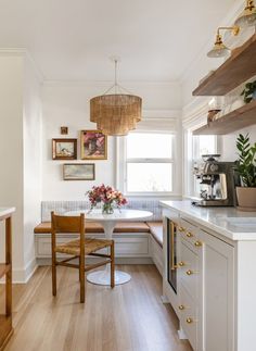 a kitchen with wooden floors and white walls, along with a breakfast nook that has built - in shelving on the wall