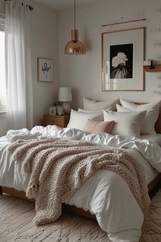 a bed with white linens and blankets in a bedroom next to a large window