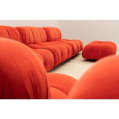 an orange couch sitting on top of a white floor next to two stools in front of it