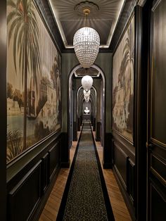 the hallway is lined with wallpaper and chandeliers, along with paintings on the walls