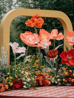 an arrangement of flowers is displayed in front of a checkered tablecloth and yellow arch