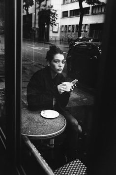 a man sitting at a table in front of a window with his hand on the plate