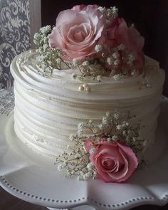 a wedding cake decorated with pink roses and baby's breath flowers on a white plate