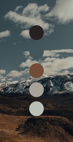 four circles are floating in the air over a desert landscape with snow capped mountains behind them