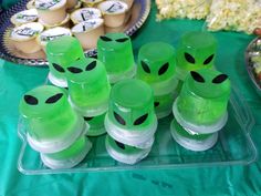 green plastic cups with black faces are on a tray next to other plates and desserts