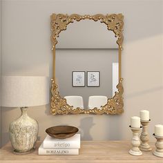 a mirror sitting on top of a dresser next to a table with candles and books