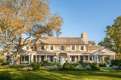 a large white house sitting in the middle of a lush green field with lots of trees