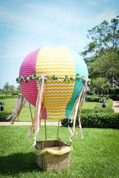 two hot air balloons with ribbons tied to them sitting in the middle of a lawn