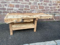 an old wooden table sitting in front of a brick wall