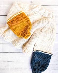 a knitted hat and sweater laying on top of a white wooden floor next to each other