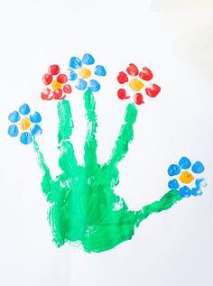 a child's hand painted with flowers on white paper and colored crayons