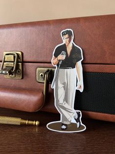 a sticker of elvis presley on top of an old suitcase with a pen next to it