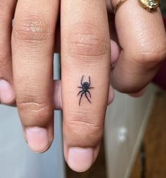 a person with a spider tattoo on their finger