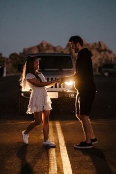 a man and woman standing in the middle of a road