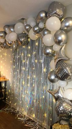 a room filled with lots of silver and white balloons