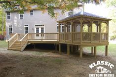 a wooden gazebo sitting in the middle of a yard next to a house with stairs leading up to it