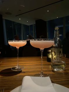 two martini glasses sitting on top of a wooden table