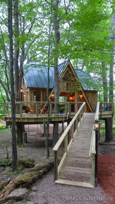 a small cabin in the woods with stairs leading to it and a deck that leads up to