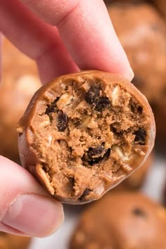 a hand holding a chocolate chip cookie in it's palm, with other cookies in the background