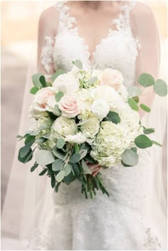 a bridal holding a bouquet of white and pink flowers with greenery on it