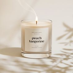 a candle with the words peach tangerine on it sitting in front of a white background