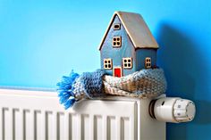 a small blue house sitting on top of a radiator next to a wall