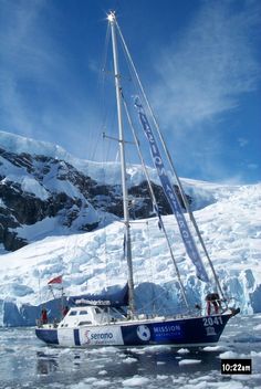 a sailboat in the middle of an ice floet with mountains in the background