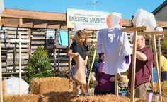 two people and a child standing in hay bales with clothes on display behind them