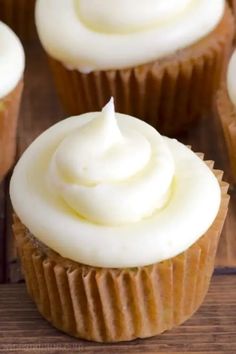 cupcakes with white frosting sitting on a wooden table