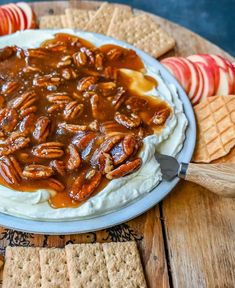 a plate filled with whipped cream and pecans on top of crackers next to an apple