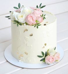 there is a white cake with pink and white flowers on the top, sitting on a plate