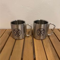 two stainless steel mugs sitting on top of a wooden table