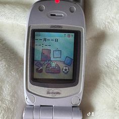 an old cell phone sitting on top of a white blanket with the screen turned off