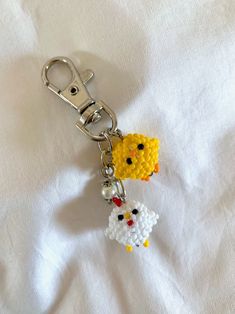 two yellow and white beads are attached to a metal keychain on a white sheet