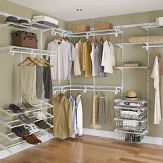 an organized closet with white shelving and clothes on hangers in the corner,