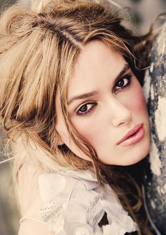 a beautiful young woman leaning against a wall