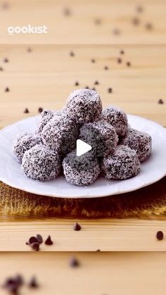 a white plate filled with chocolate covered donuts on top of a wooden table next to coffee beans