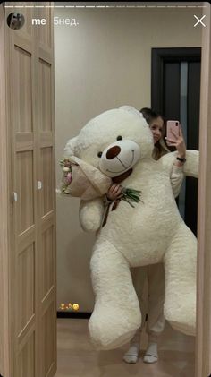 a woman holding a large white teddy bear in her arms while taking a selfie