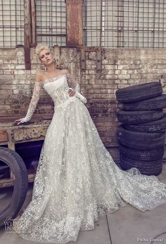 a woman in a white wedding dress standing next to tires and looking at the camera