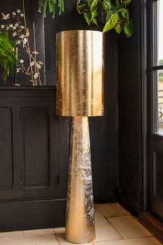 a gold lamp sitting on top of a table next to a potted plant