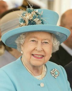 an older woman wearing a blue hat and pearls