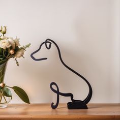 a vase with flowers in it and a metal dog figure next to it on a table