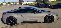 a silver sports car is parked on the side of the road with other cars behind it