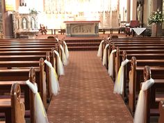 rows of pews in a church decorated with white tulle skirtes and flowers