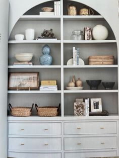 a white bookcase filled with lots of books next to a vase and other items