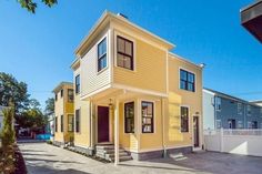 two story yellow house with red door and windows