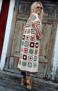 a woman standing in front of a wooden door wearing a crocheted granny outfit