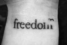 a black and white photo of a person's wrist with the word freedom written on it