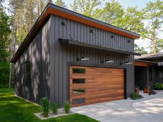 two garages with wooden doors and windows in the middle of a grassy area next to trees