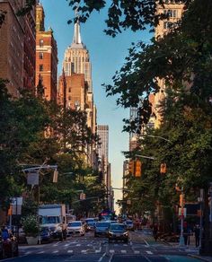 an empty city street with tall buildings in the back ground and cars parked on the side